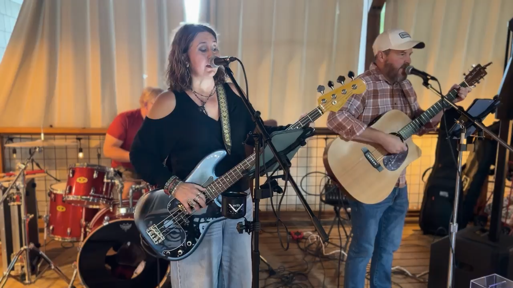Dr. Amy Eubanks playing guitar on stage for charity concert